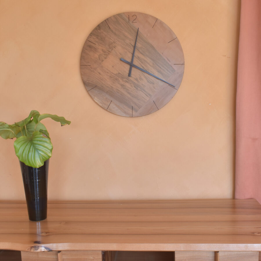 scène d'intérieur avec plante verte et horloge murale ronde en bois sur mur rose