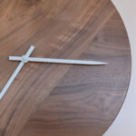 détail d'horloge murale ronde en bois sombre et aiguilles blanches
