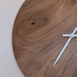détail d'horloge murale ronde en bois sombre et aiguilles blanches