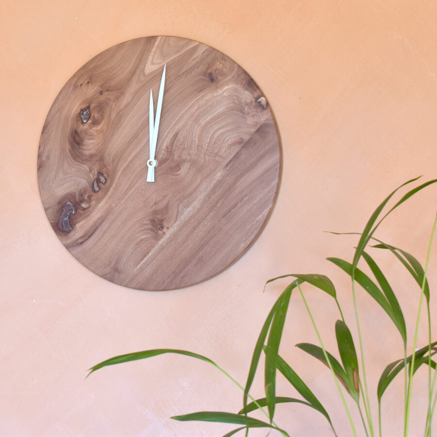 plante verte et horloge murale ronde en bois sur mur rose